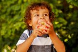 Kinderernährung: Kind beißt in einen Apfel