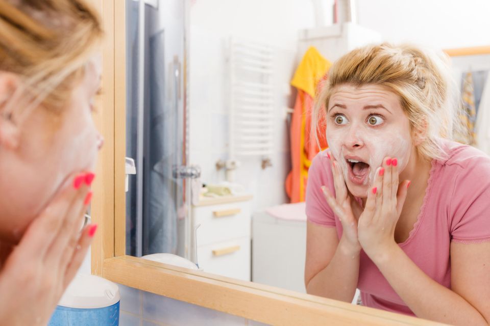 3 Zeichen, dass du unbedingt etwas an deiner Gesichtspflege ändern solltest: Geschockte Frau vor dem Spiegel