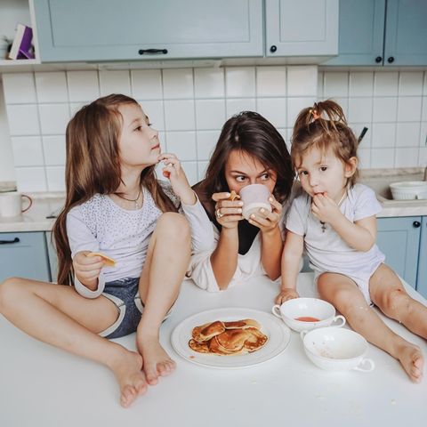 Mental Load: Mutter isst mit ihren zwei Kindern in der Küche