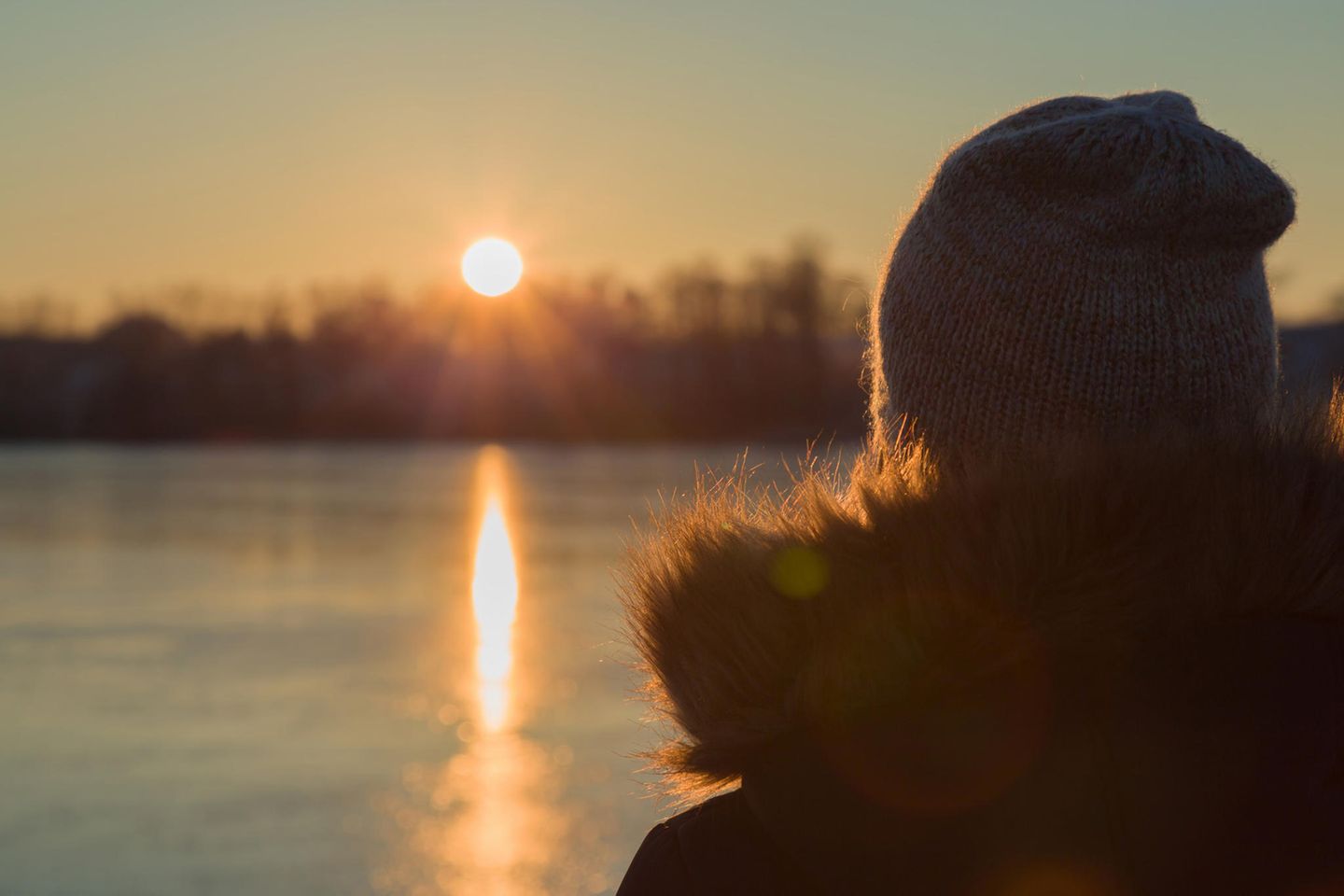 Erfahrungsbericht: Eine Frau schaut sich einen Sonnenuntergang am See an
