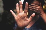 Frauenfeindliche Gesetze: Eine schwarze Frau hält schützend die Hand vor ihr gesicht