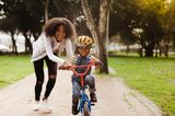 Erziehung: Mama hilft Sohn beim Radfahren