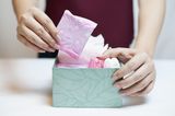 Eine Frau packt Tampons und Binden in eine Box
