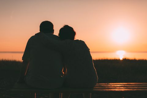 Partner loslassen: Paar sitzt vor Sonnenuntergang