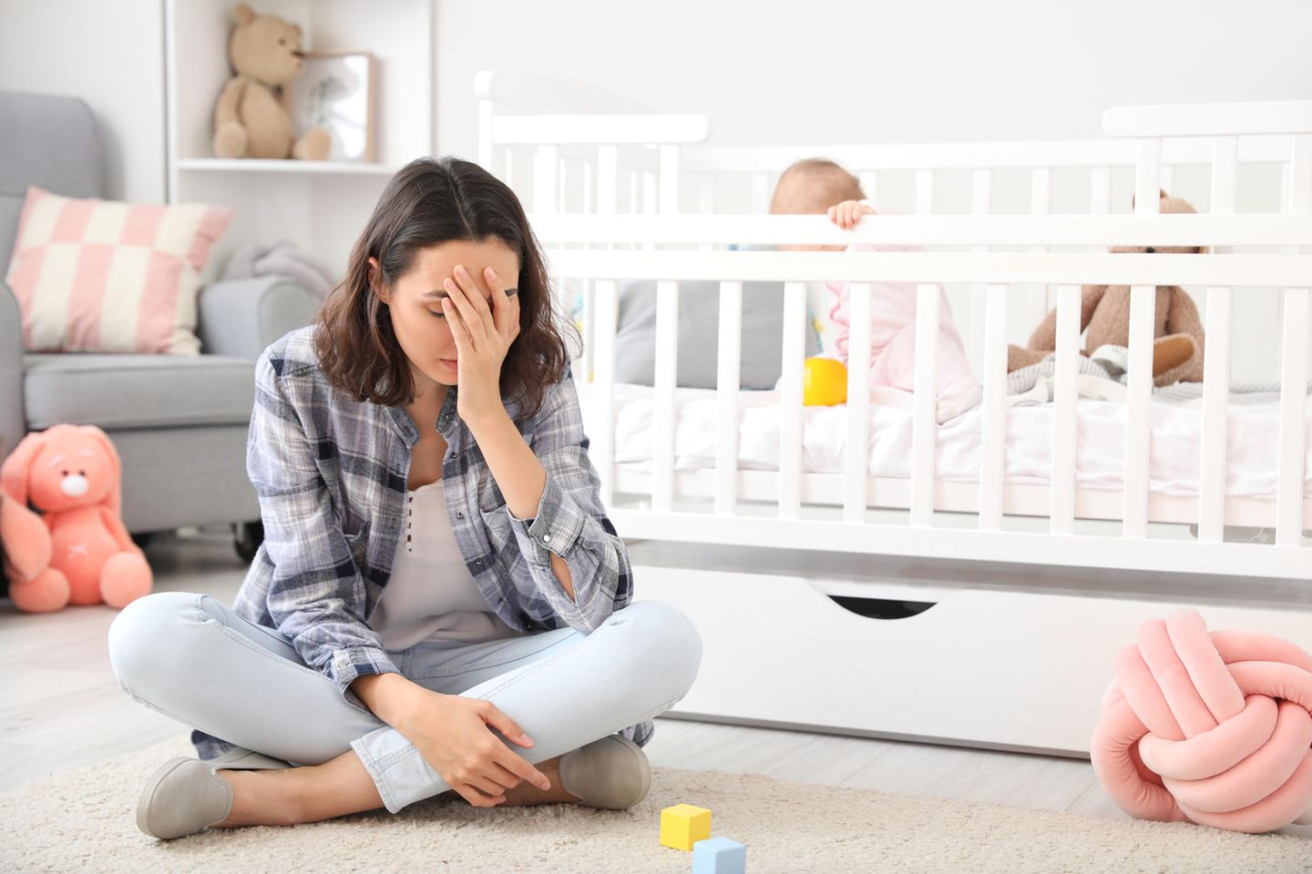 Experteninterview: Deprimierte Frau vor Kinderbett