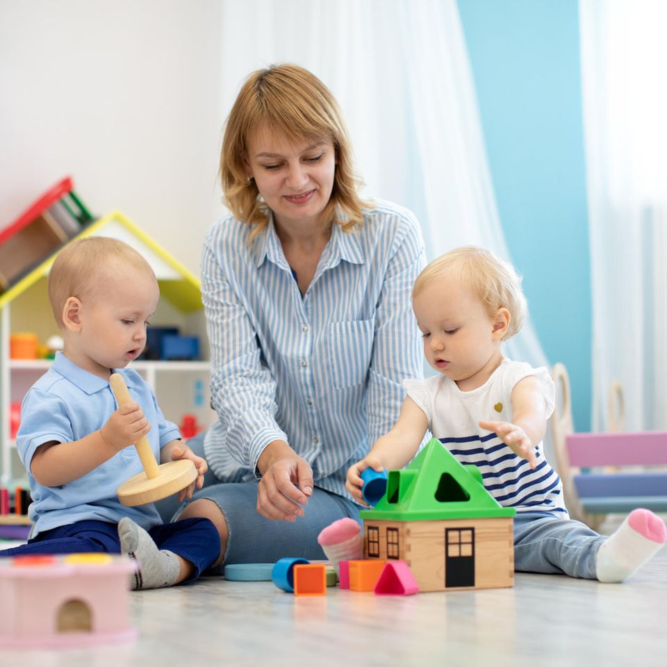 Kinderbetreuung: Kinder spielen mit Frau