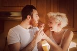 Eine Frau füttert ihren Partner und lacht