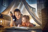 Kinderbetreuung: Junge Frau liest Kind ein Buch vor