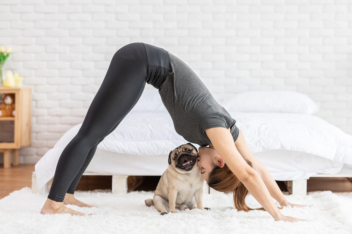 Eine Frau in einer Yoga-Pose mit Mops