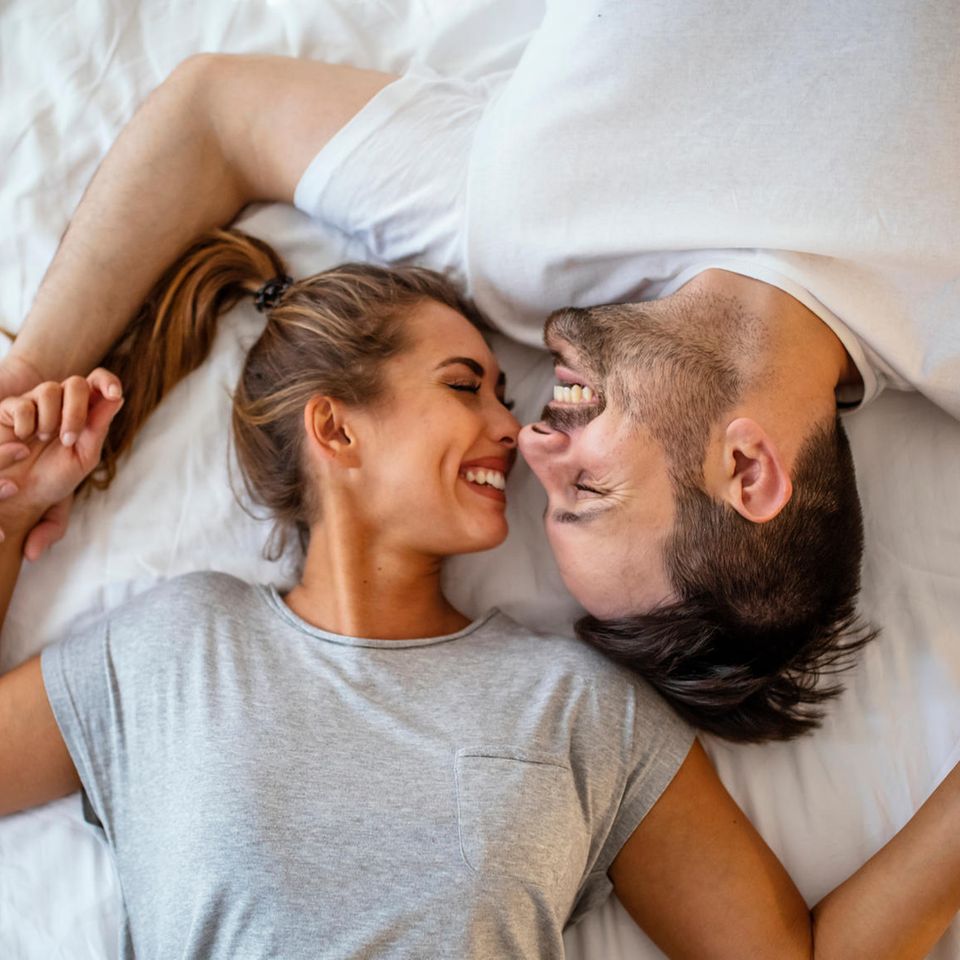 Karezza: Mann und Frau lächeln sich im Bett an