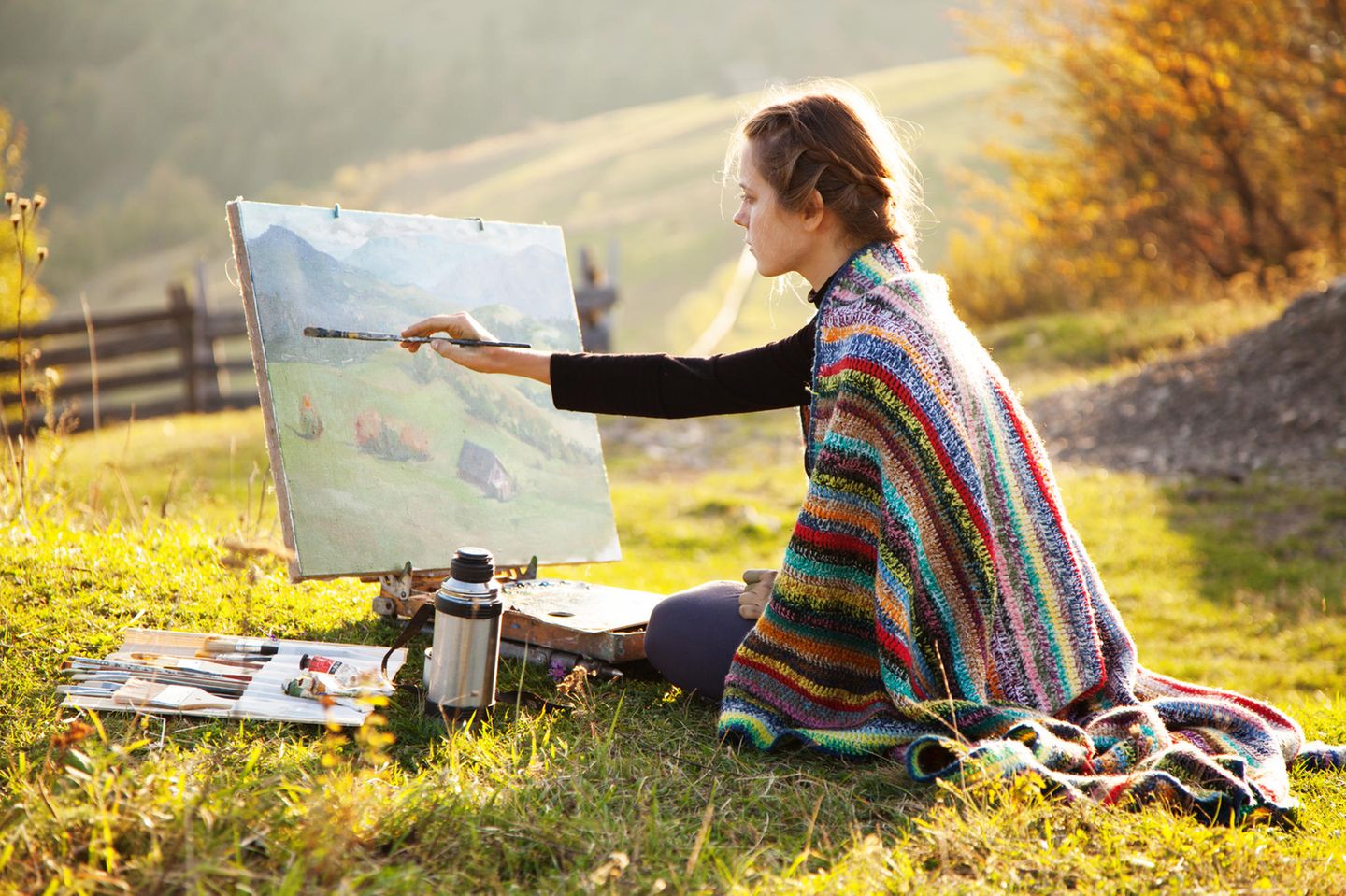 Eine Frau malt ein Bild in einer Herbstlandschaft