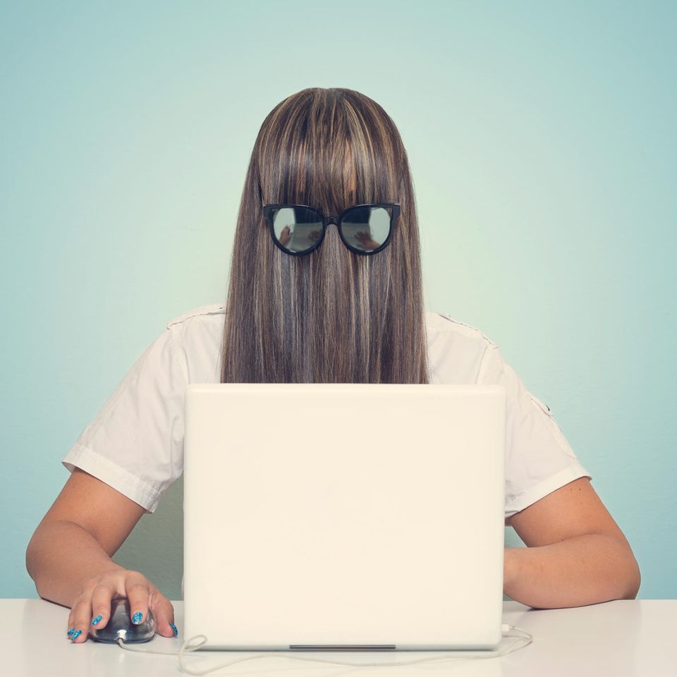 Frau mit Haaren und Brille vor dem Gesicht, sitzt am Laptop