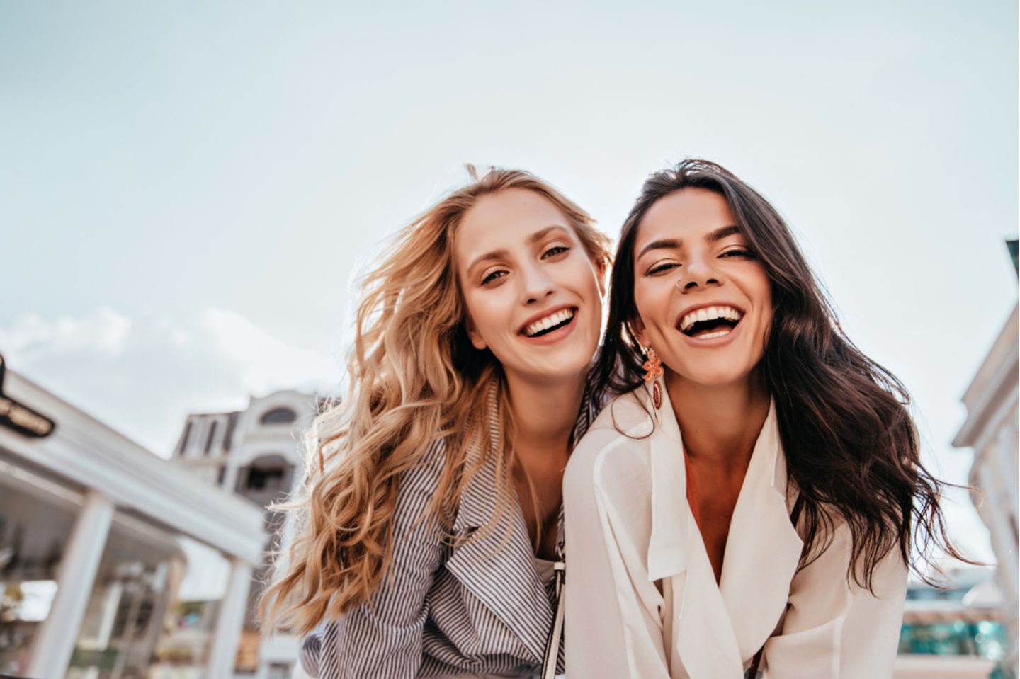 Naturlocken stylen: Zwei lächelnde Frauen mit lockigen Haaren.