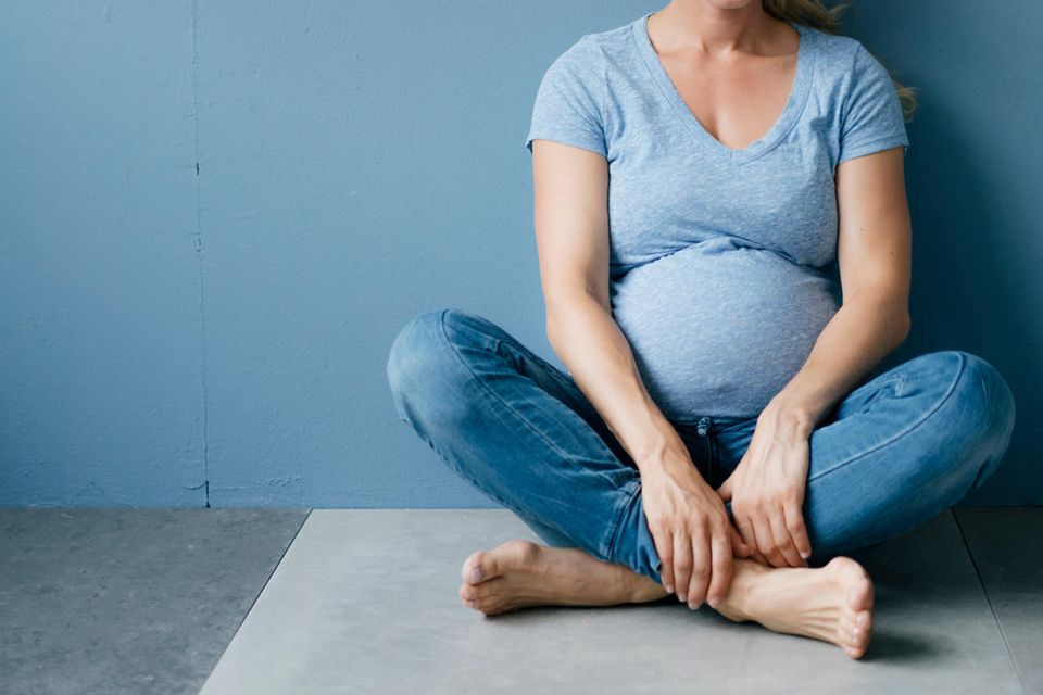 Schwangere Frau vor blauem Hintergrund