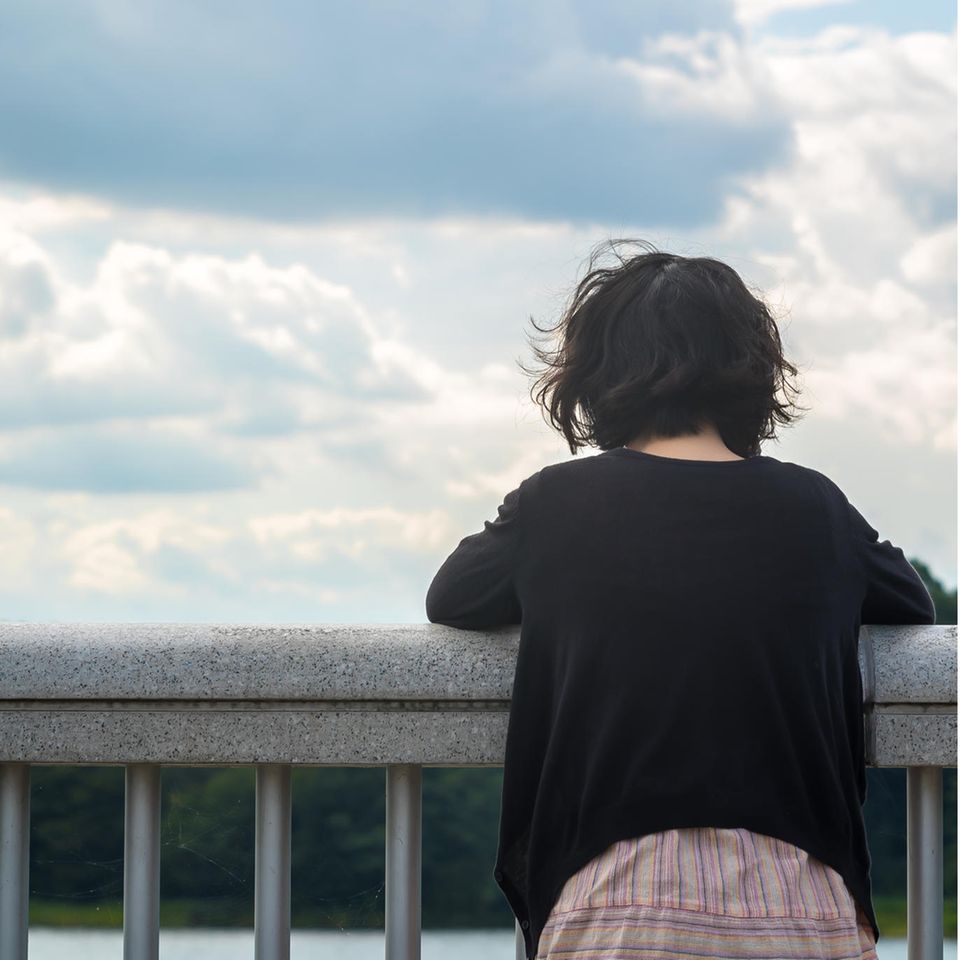 Suizidgedanken: Eine Frau steht am Geländer und denkt nach