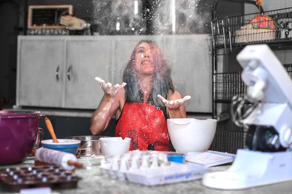 Frau in Küche wirft Mehl nach oben