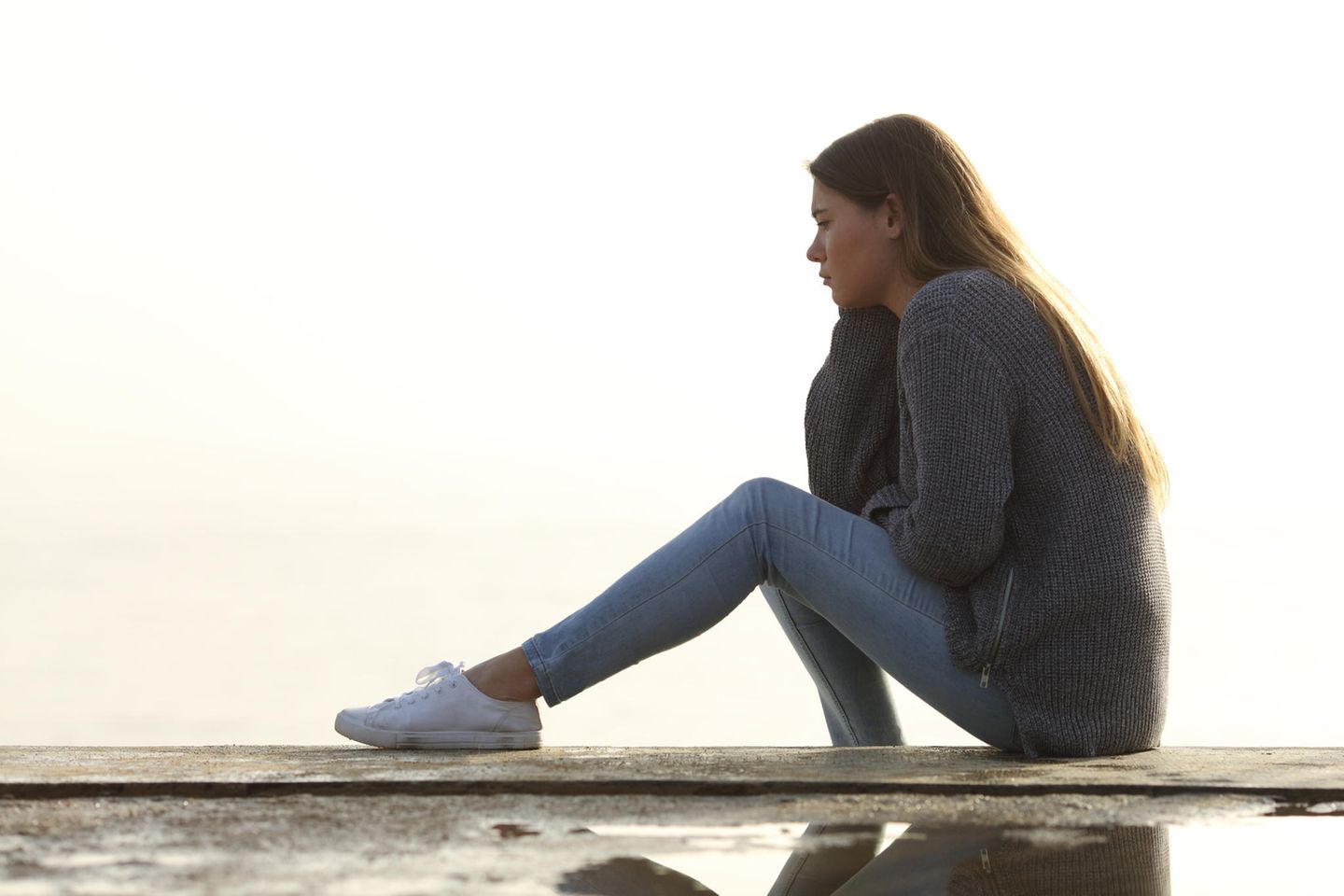 Macht der Gewohnheit: Eine traurige Frau sitzt auf einer Mauer