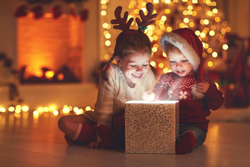 Weihnachten mit Kindern: Zwei Kinder packen Geschenk aus