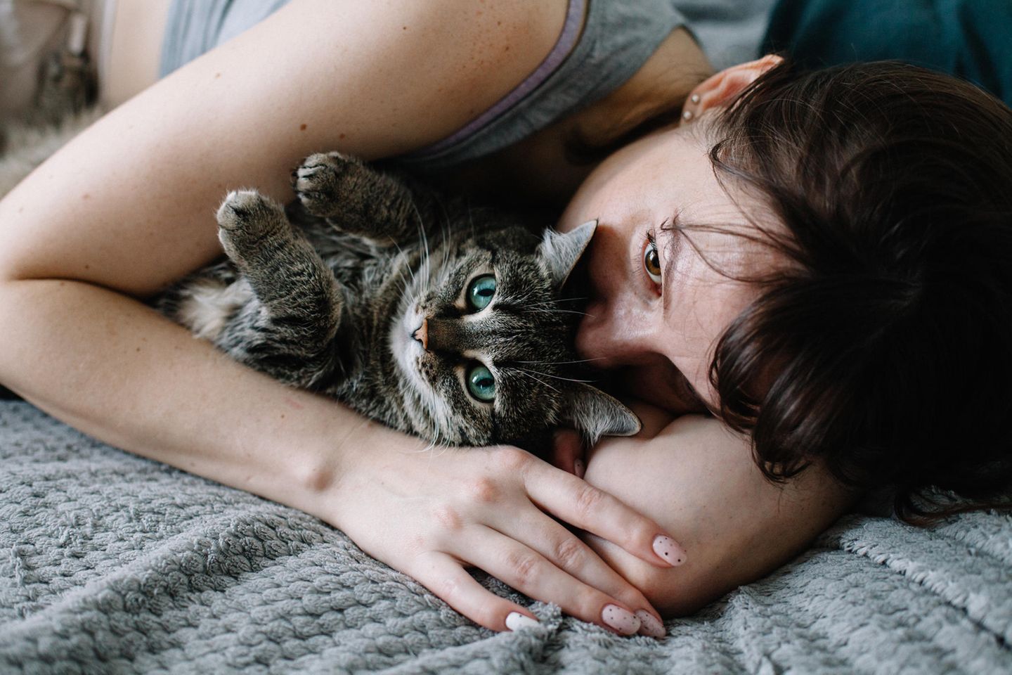 Verletzte Gefühle: Frau liegt mit Katze im Bett