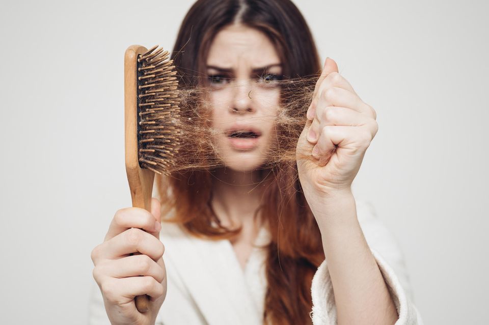 Frau zieht Haare aus einer Bürste