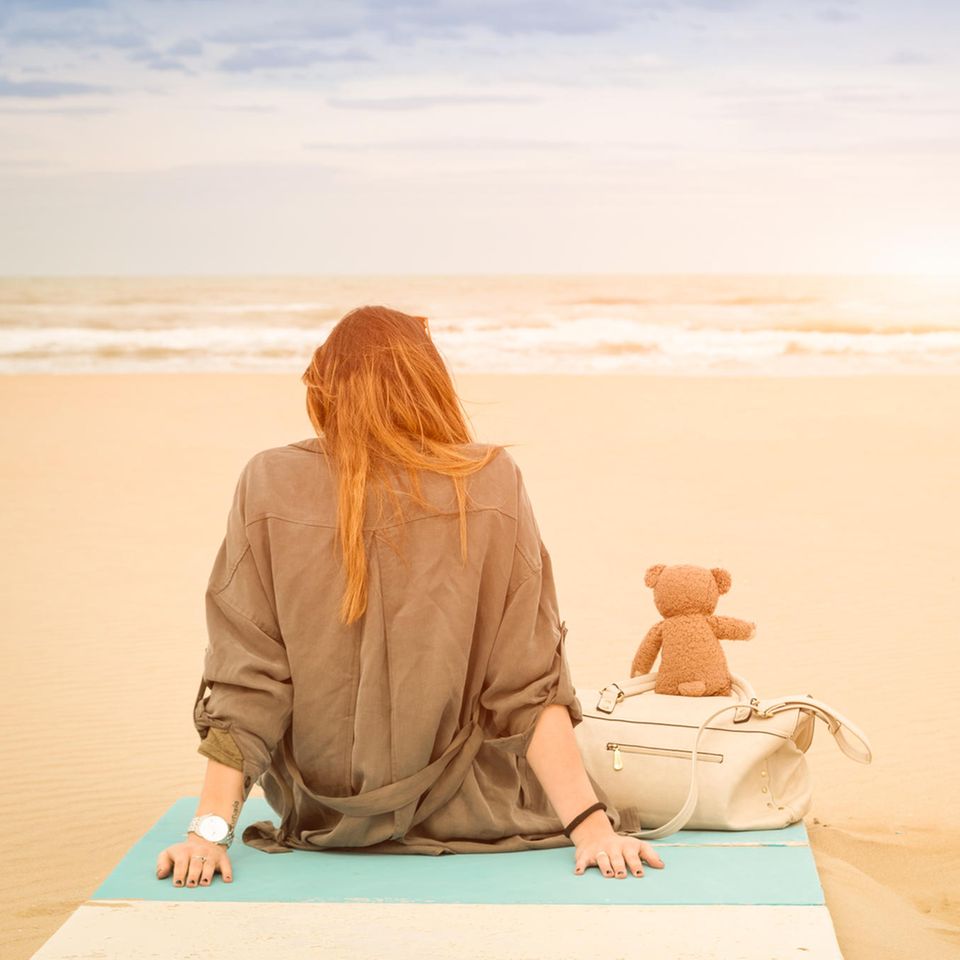 Whisper: Eine Frau sitzt am Strand mit einem Teddy