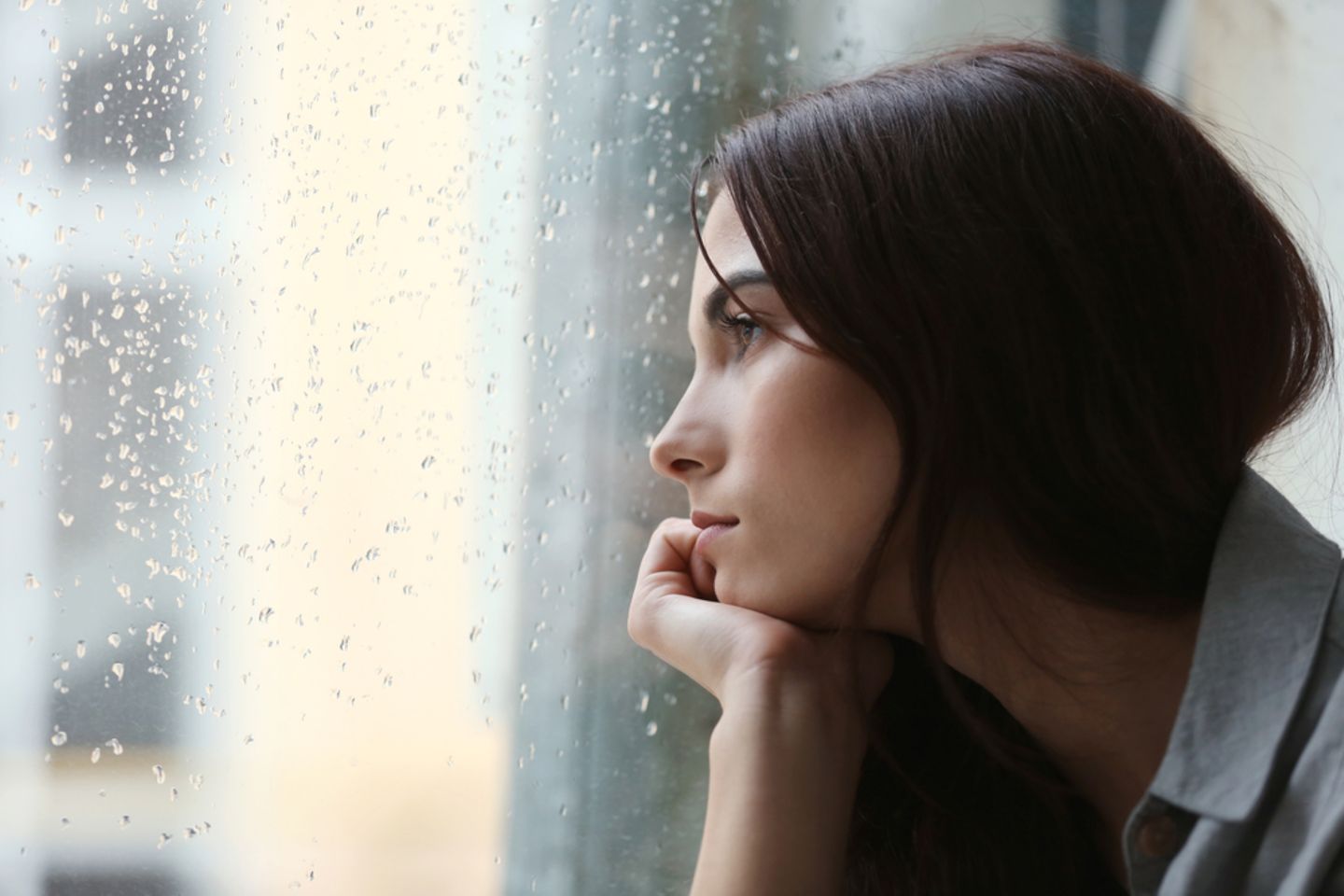 Corona aktuell: Traurige Frau sieht aus dem Fenster