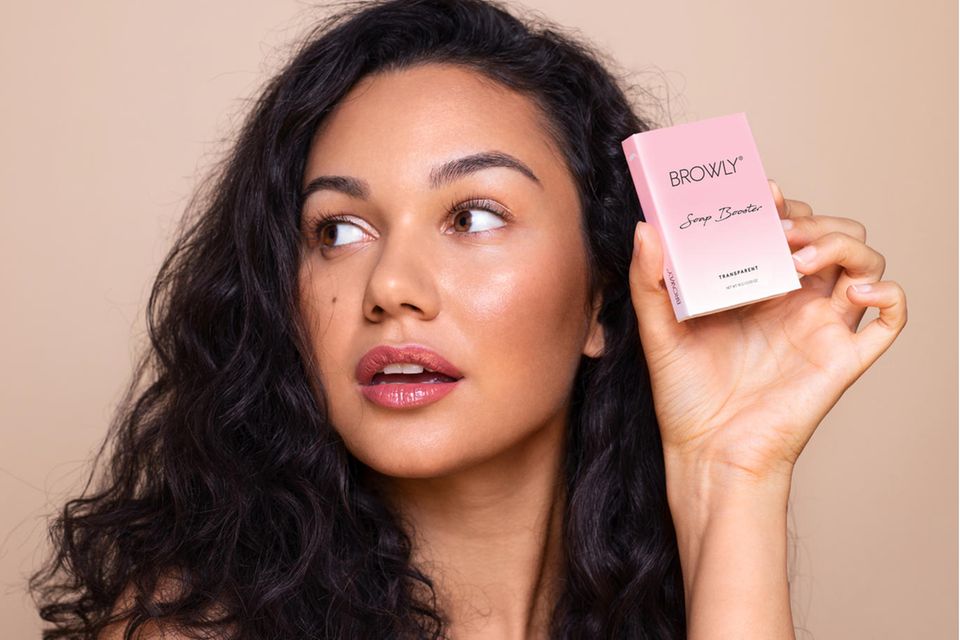 Brunette woman holds brow soap in her hand