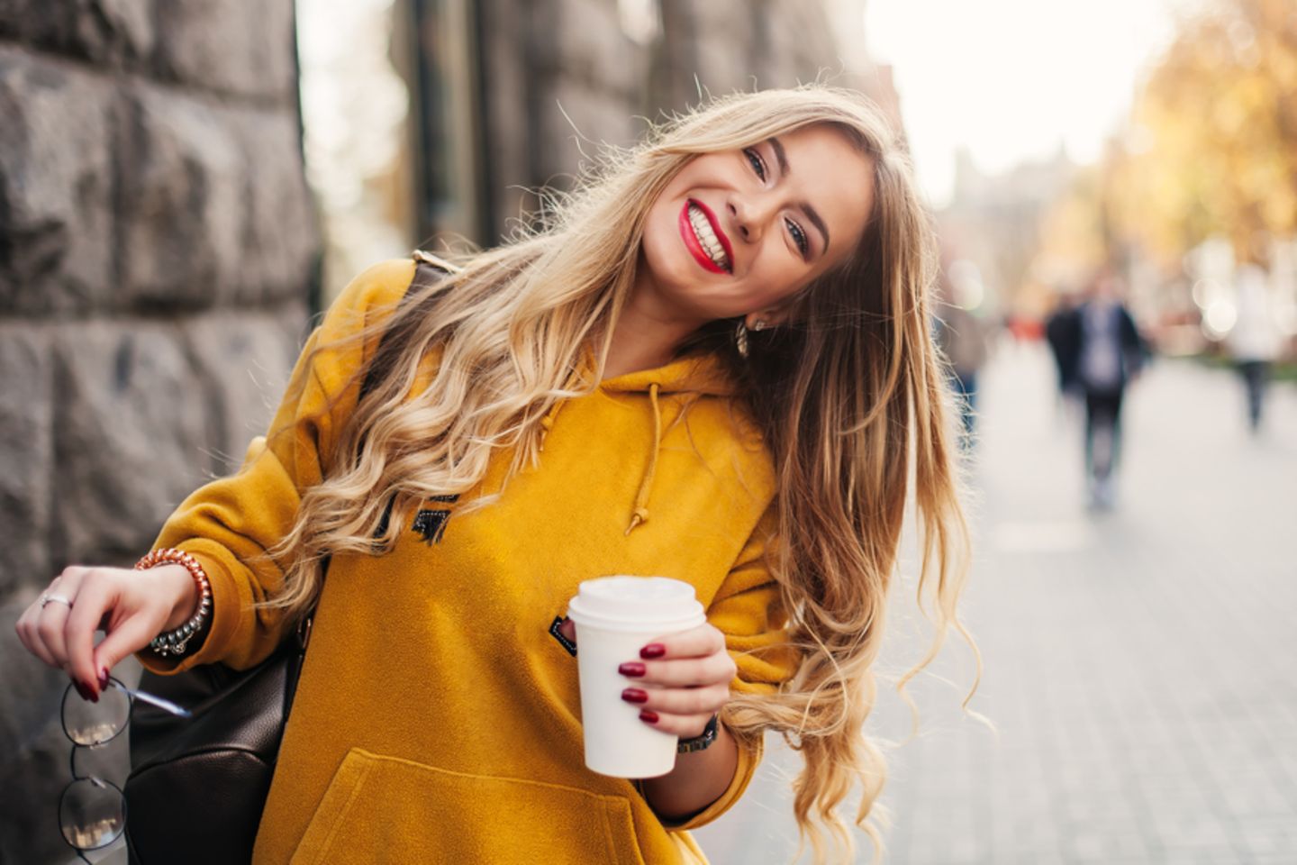 Resilienz stärken: Lächelnde Frau mit einem Kaffee in der Hand.
