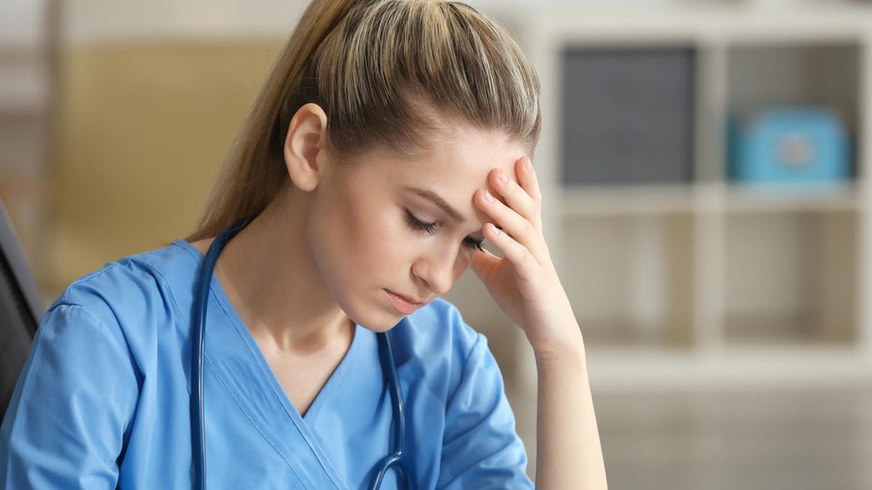 Krankenschwester sitzt traurig am Tisch