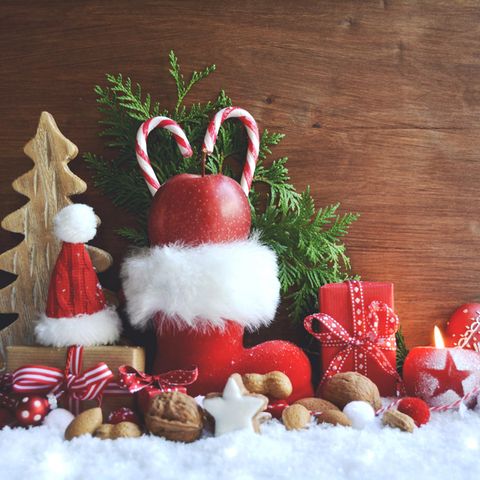 Nikolaus-Geschenkideen: roter Nikolausstiefel, Nüsse, Zimtsterne, Kunstschnee, Tannenzweig, kleine Geschenke, Weihnachtsdeko