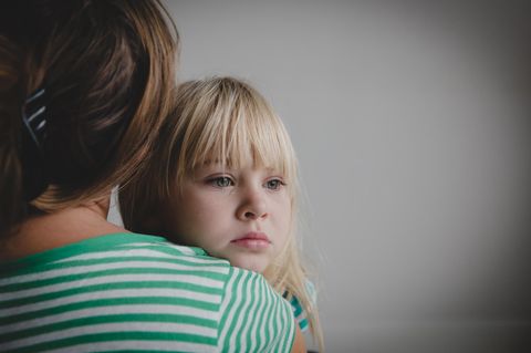 Kinder fördern: Trauriges Kind auf dem Arm der Mutter