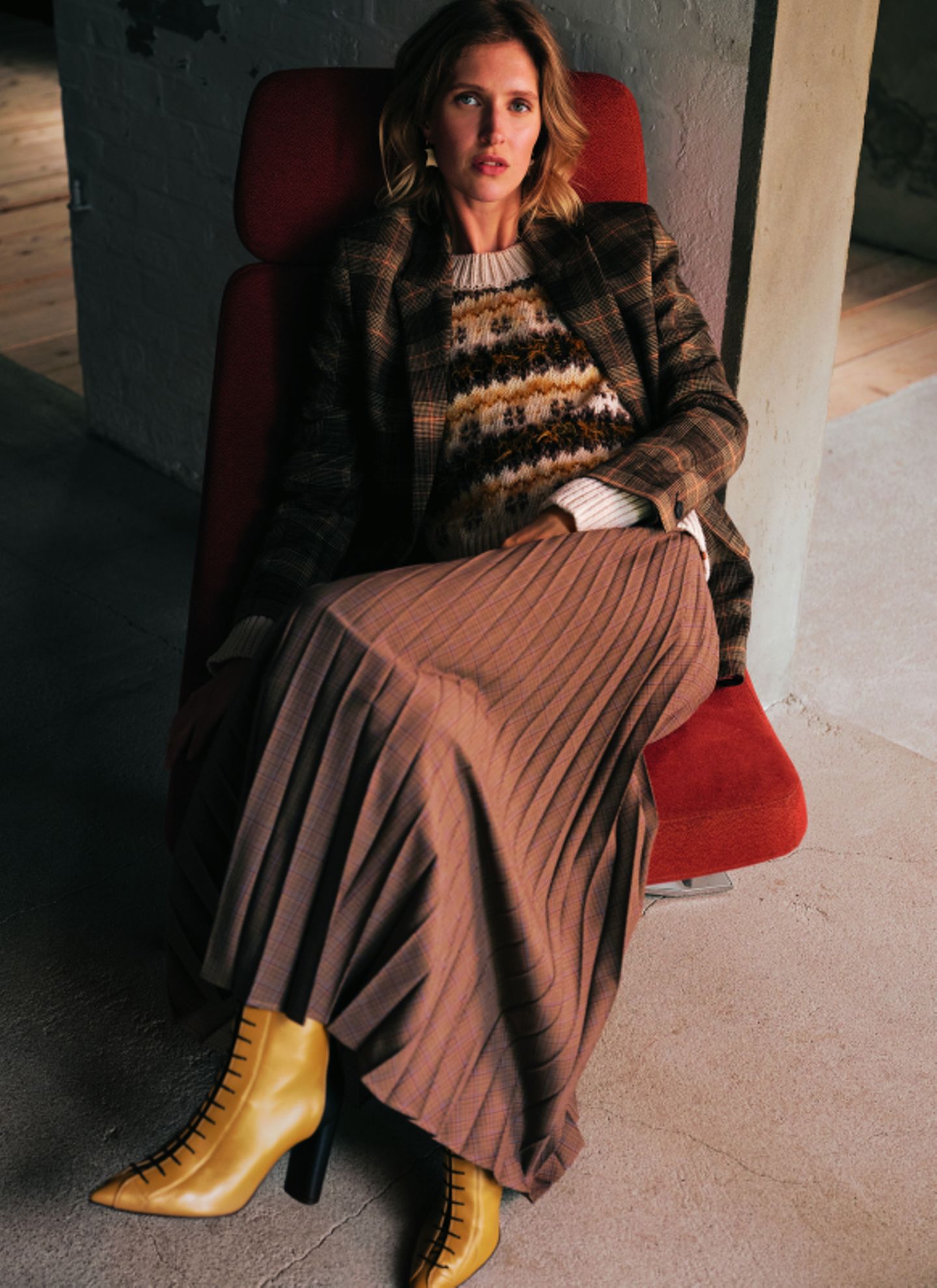 Zweiteiler für Damen: Model auf Sessel mit langem Rock und Strickpullover
