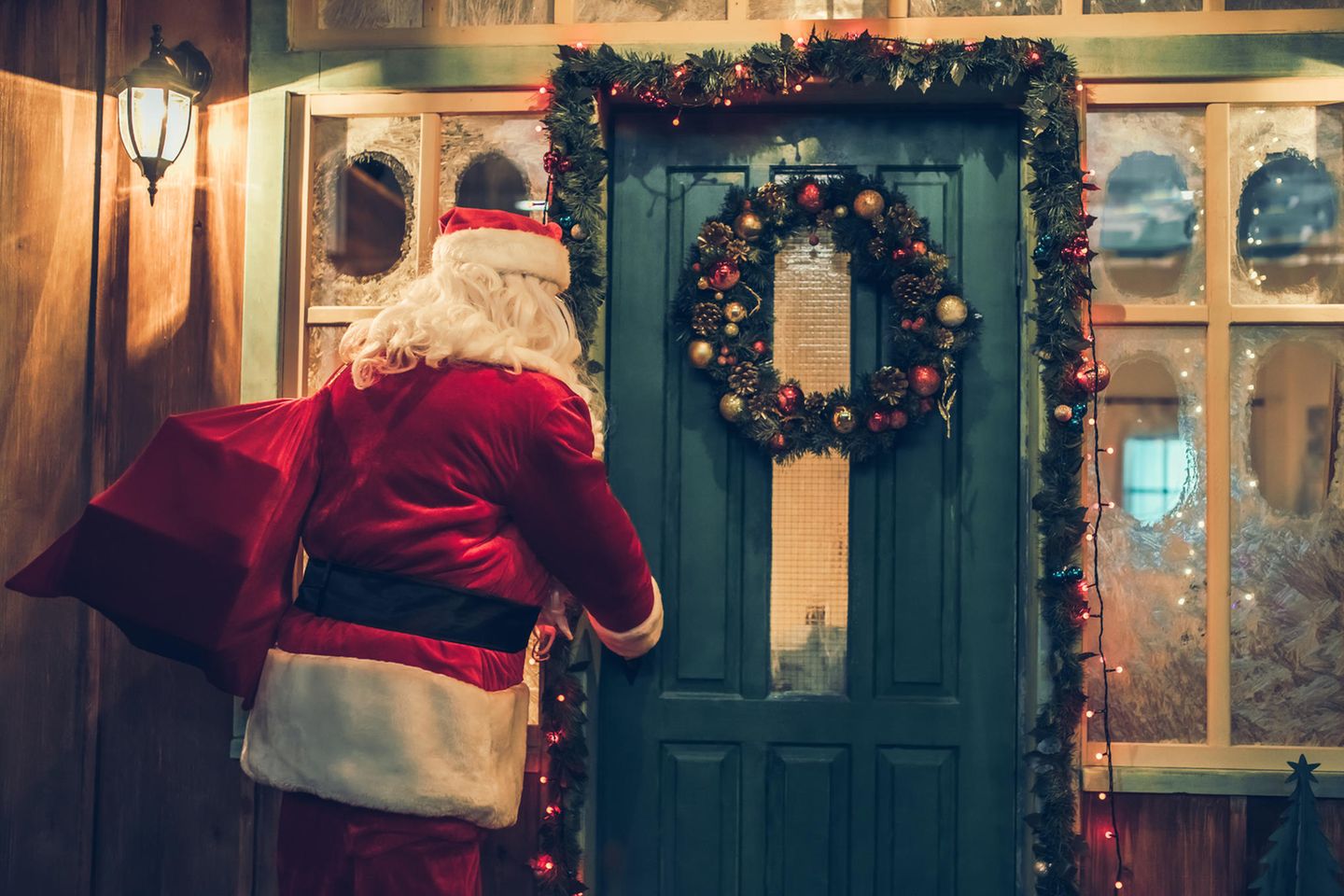 Weihnachtsmann mit Geschenken vorm Haus