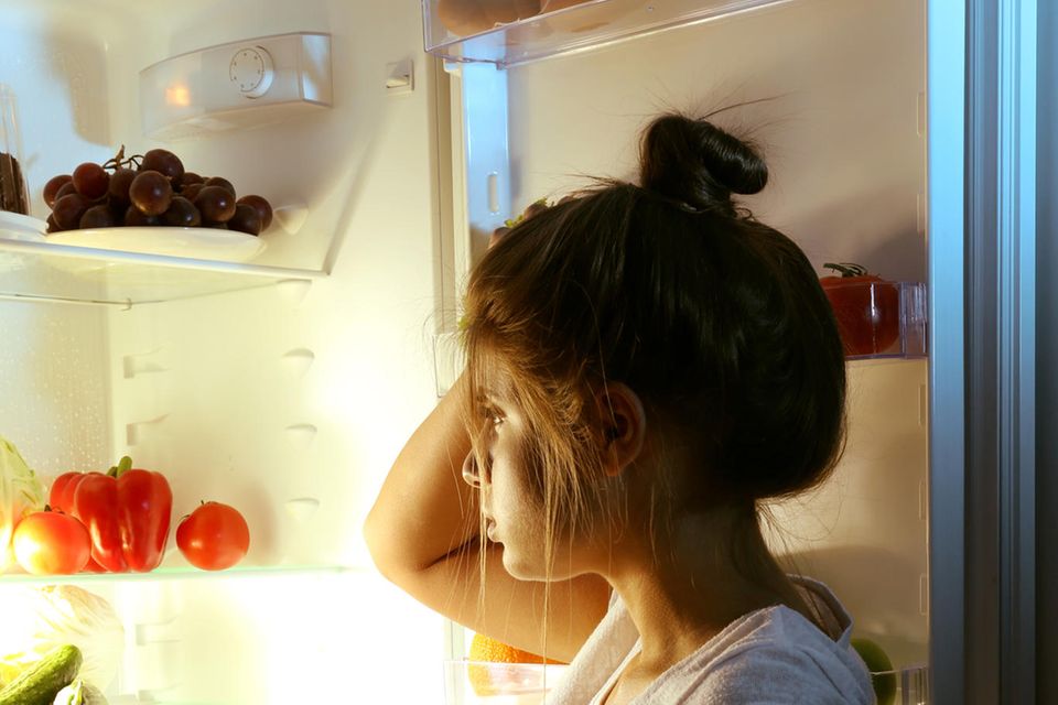 Hungergefühl: Frau vor offenem Kühlschrank