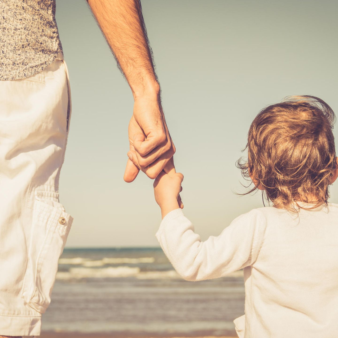 Väter-Zweifel: Mann hält Kind an der Hand