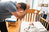 Väter-Zweifel: Vater steht verzweifelt am Bett seines Babys