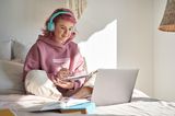 Eine Frau sitzt im Schneidersitz vor ihrem Laptop