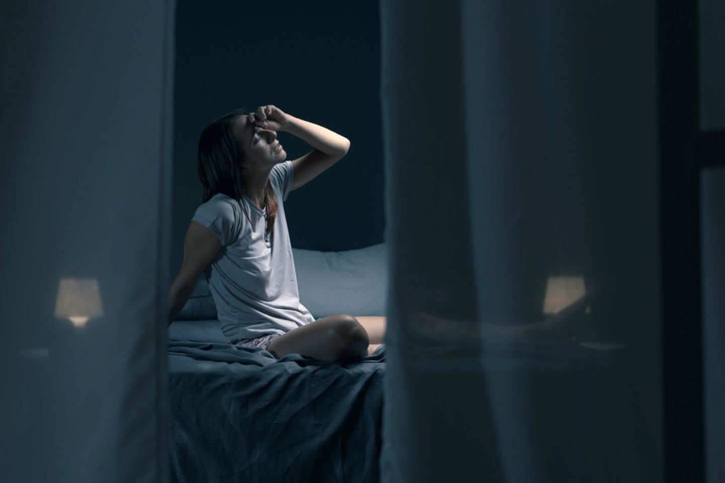 Mit offenem Fenster schlafen: Müde Frau im Dunklen