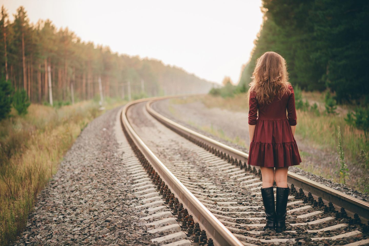 Verhaltensökonomie: Eine Frau steht auf Bahngleisen und schaut in die Weite