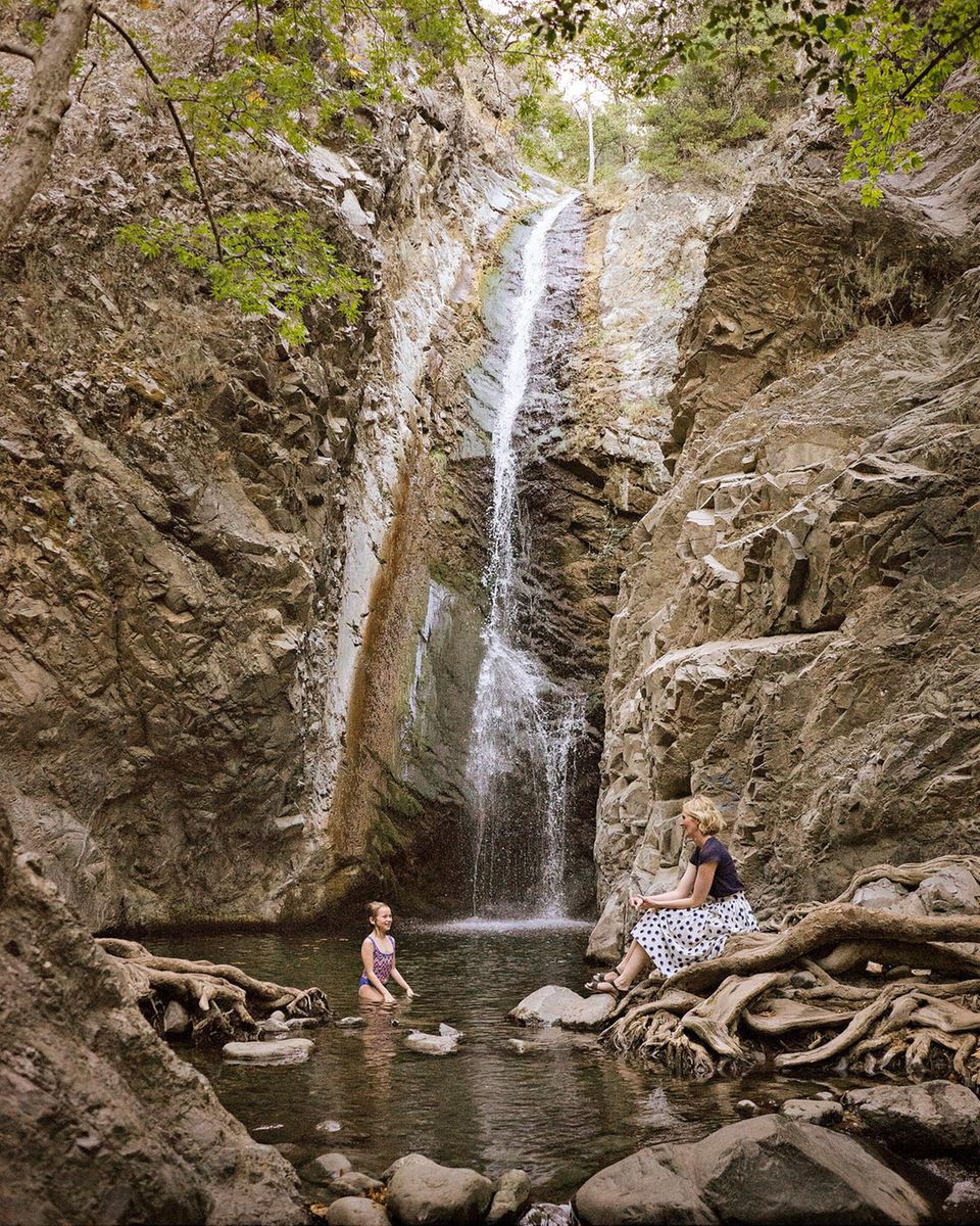 Cyprus: girl stands in the water at the waterfall