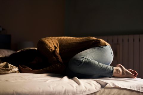 Frau liegt verzweifelt auf Bett