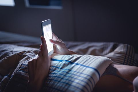 Ghostdating: Eine Frau in der Nacht mit einem Handy in der Hand