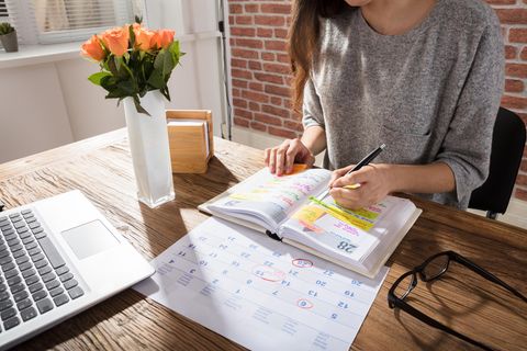 Selbstorganisation: Frau schreibt Notizen in einen Kalender.