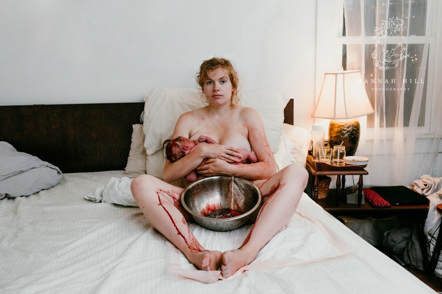 Geburtsfotos 2021: Frau sitzt mit Baby auf Bett