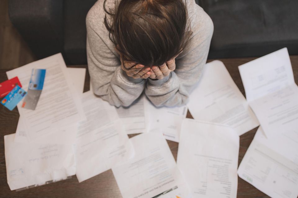 5 Gedanken, die Versagensängste auslösen: Frau sitzt verzweifelt über Rechnungen