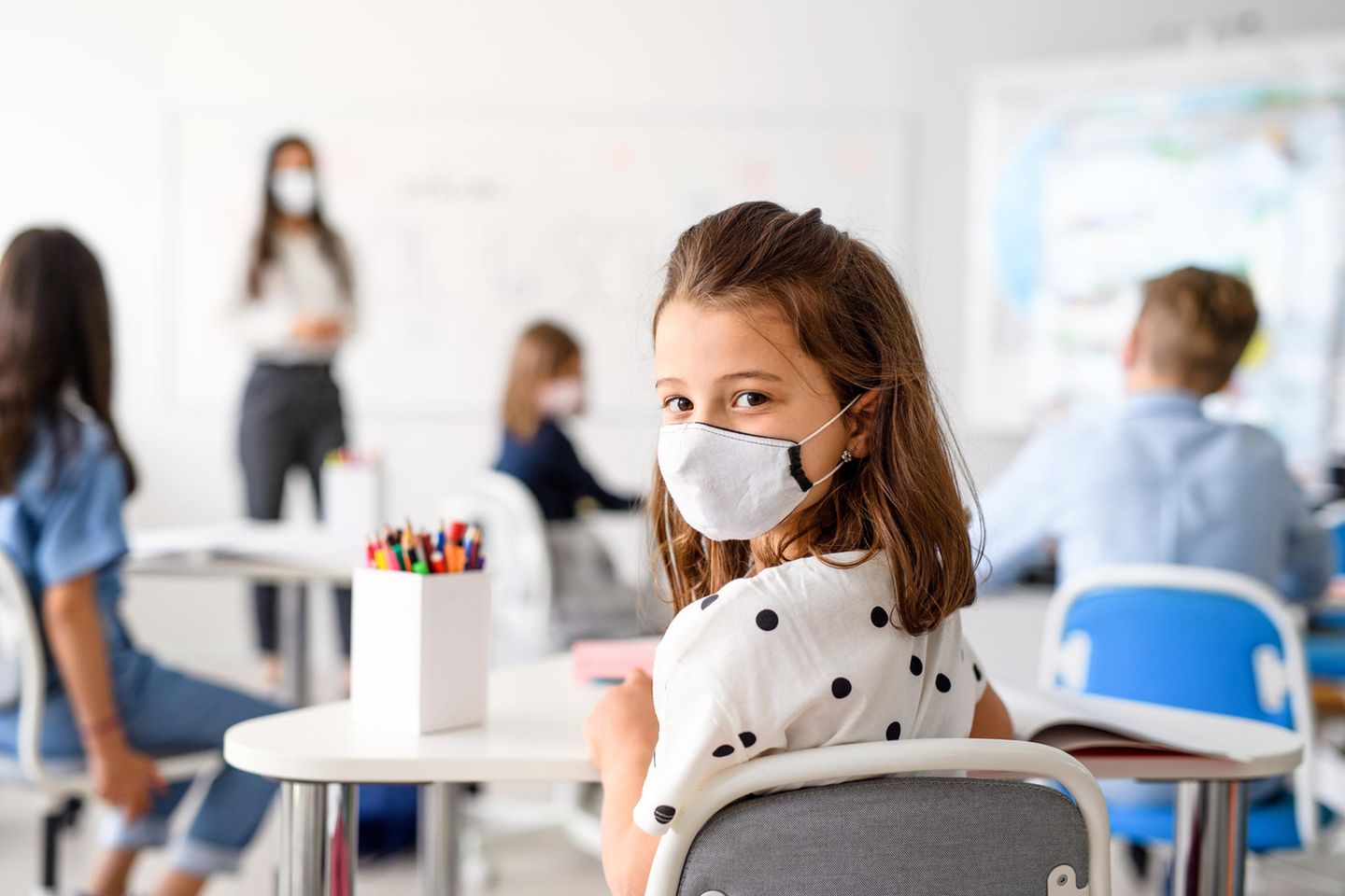 Corona aktuell: Schulkind mit Maske im Klassenzimmer