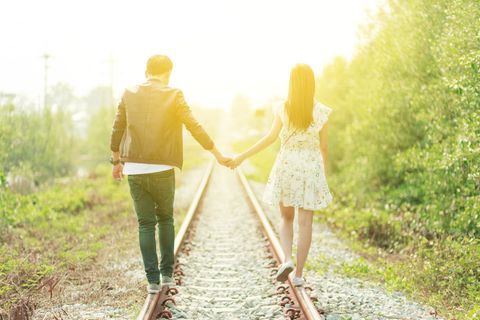 Psychologie: Ein Paar spaziert Hand in Hand über Bahnschienen