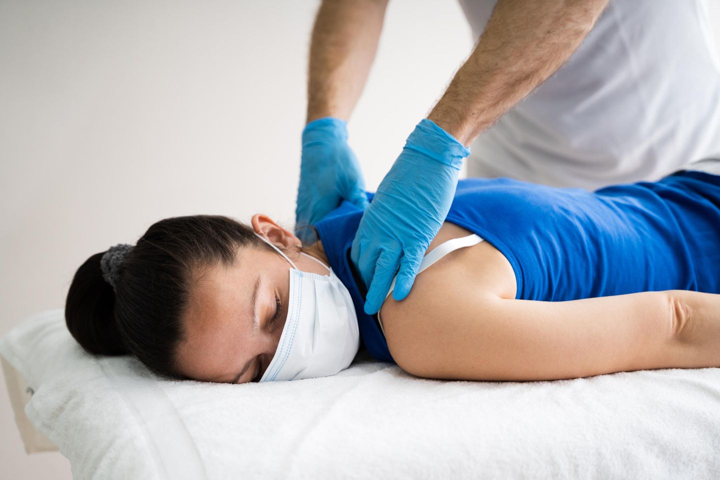 Corona-Ausbruch: Frau mit Mundschutz bei der Physiotherapie