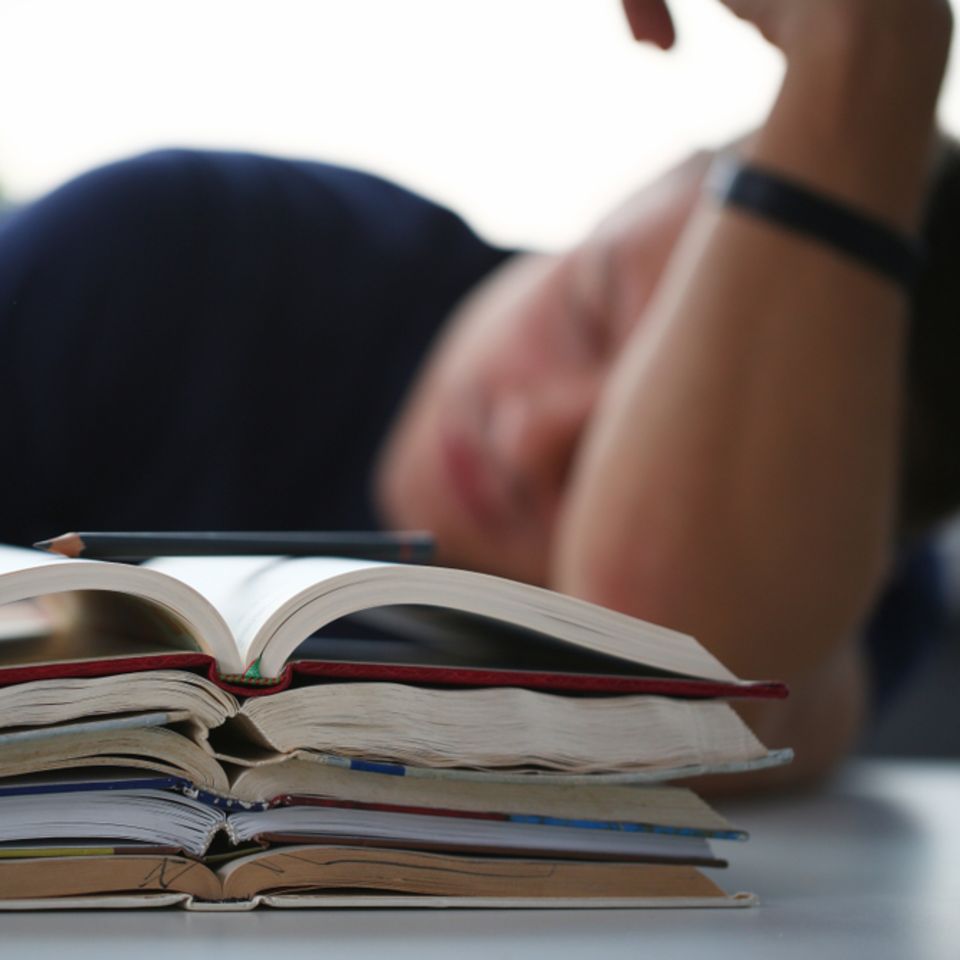 Schlau träumen: schlafender Mann vor Büchern