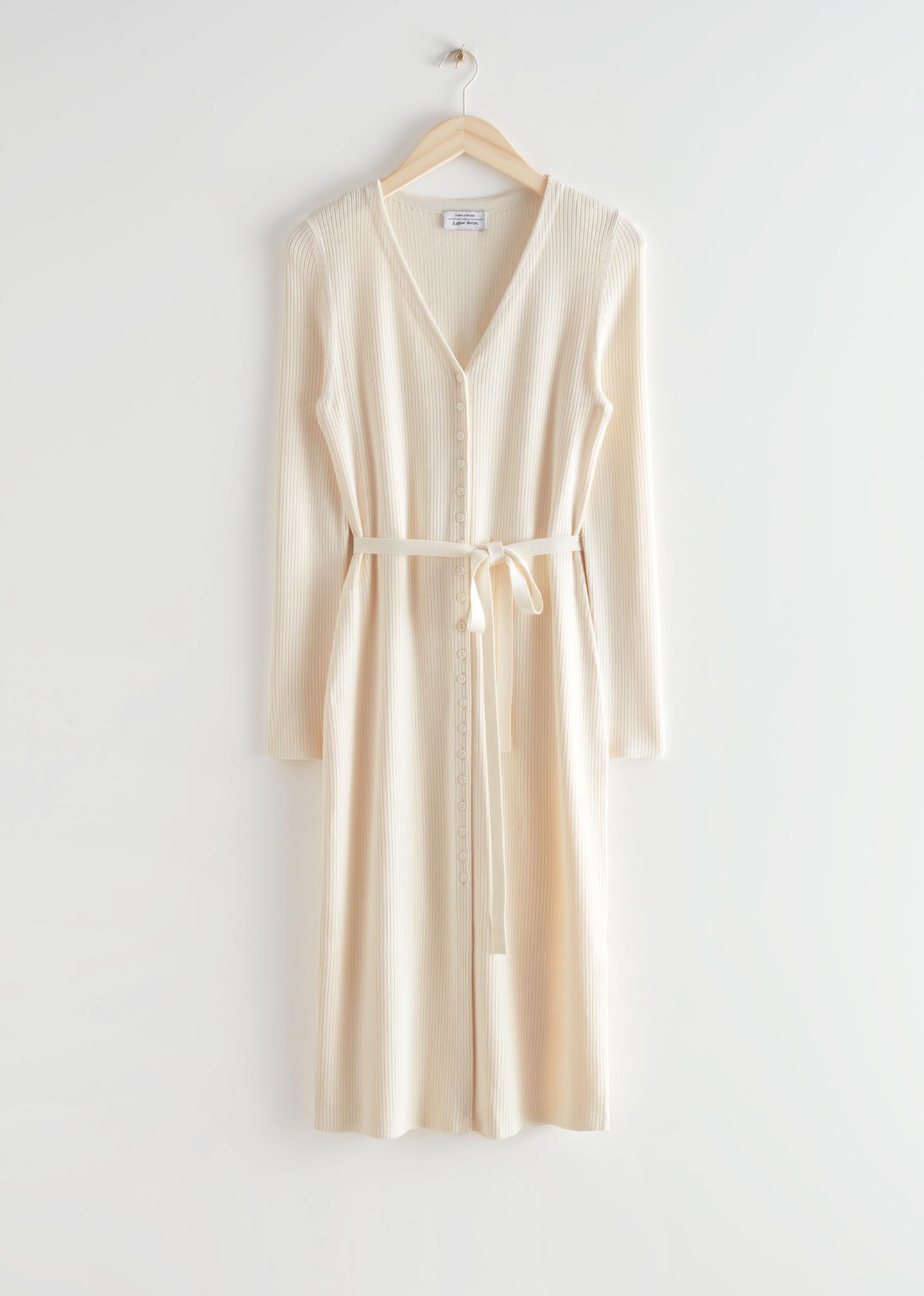 Dieses Strickkleid mit V-Ausschnitt und Knopfleiste in zartem Gelb ist perfekt für die Übergangszeit. Dank des dünnen Bändchens an der Taille und der hoch beginnenden Knopfleiste ein absoluter Figurschmeichler. Von &OtherStories, 99 Euro